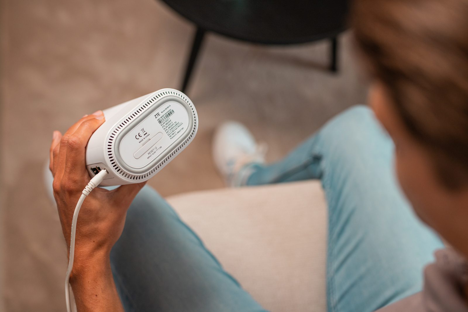 Hand houdt een wit modem vast, met de onderkant en het typeplaatje in beeld