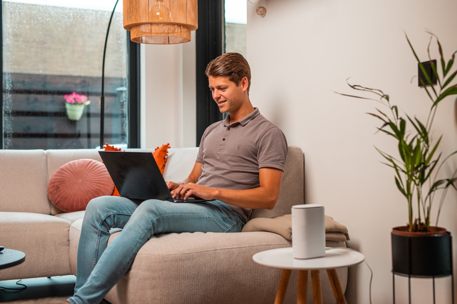 Man op de bank met een laptop, het 5G-modem op het bijzettafeltje
