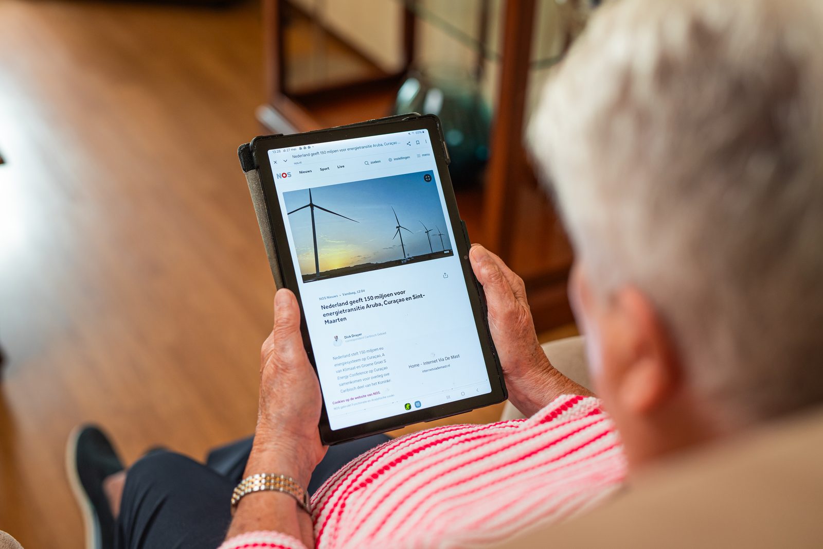 Vrouw leest een nieuwsbericht op een tablet in de woonkamer