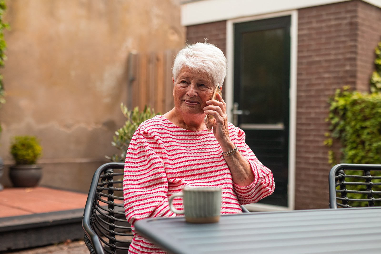 Vrouw belt buiten aan de tuintafel