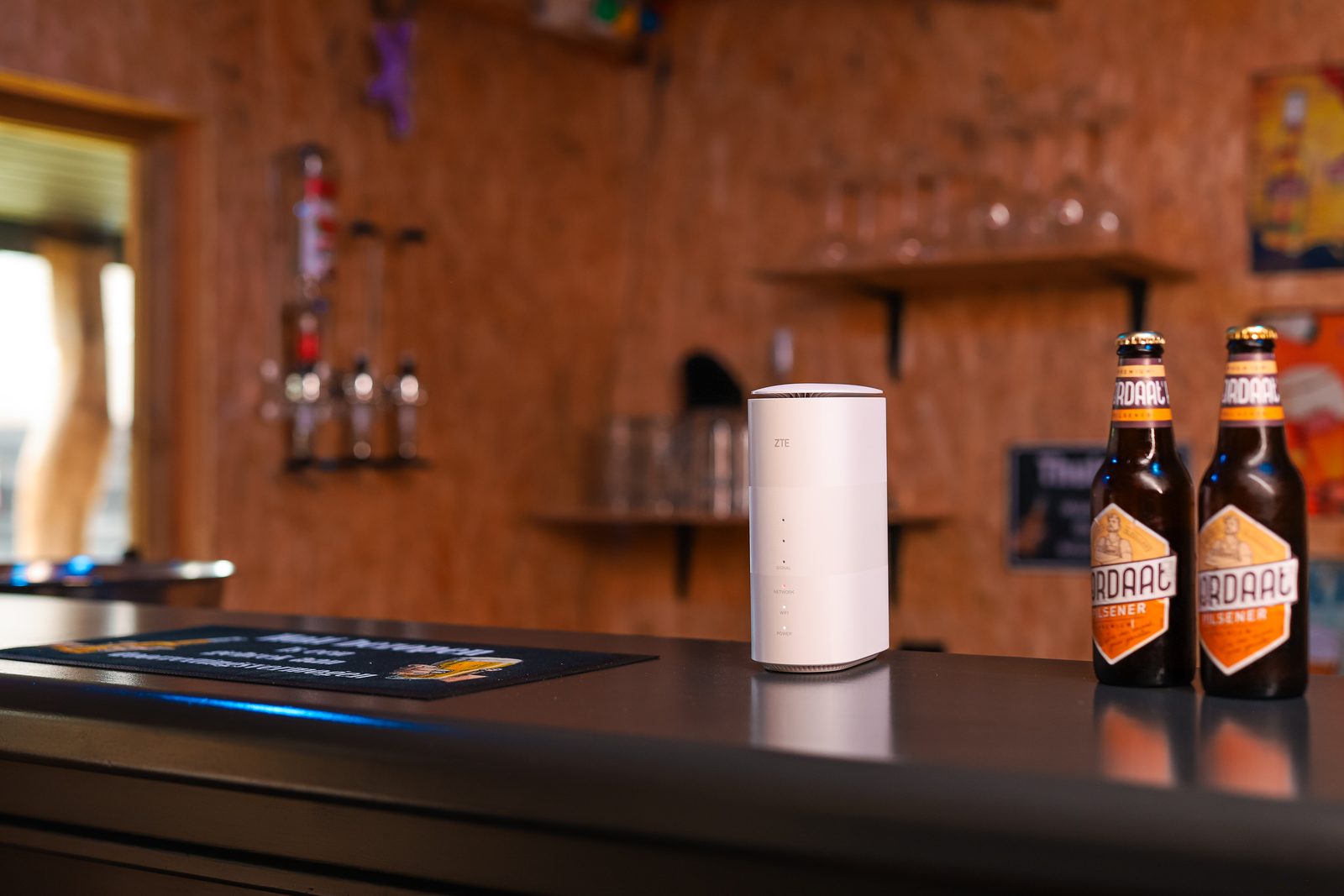 Wit 4G/5G-modem op de bar van een horecazaak, naast twee bierflesjes