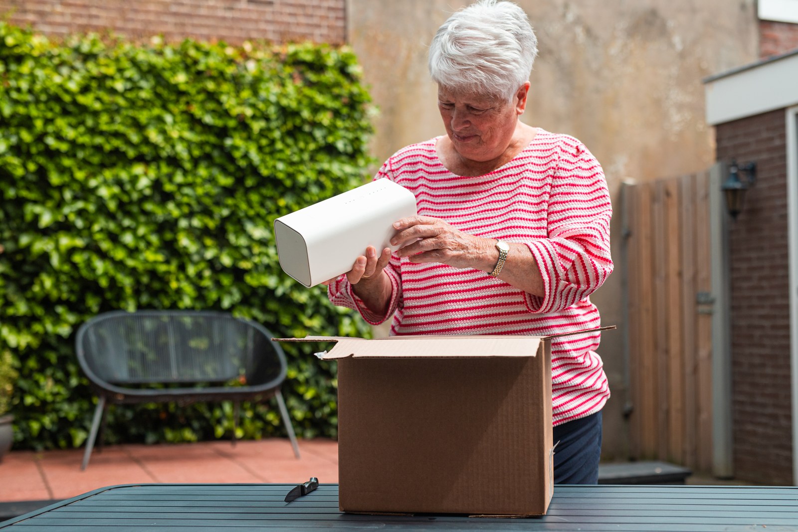 Vrouw pakt het 5G-modem uit een doos in de tuin