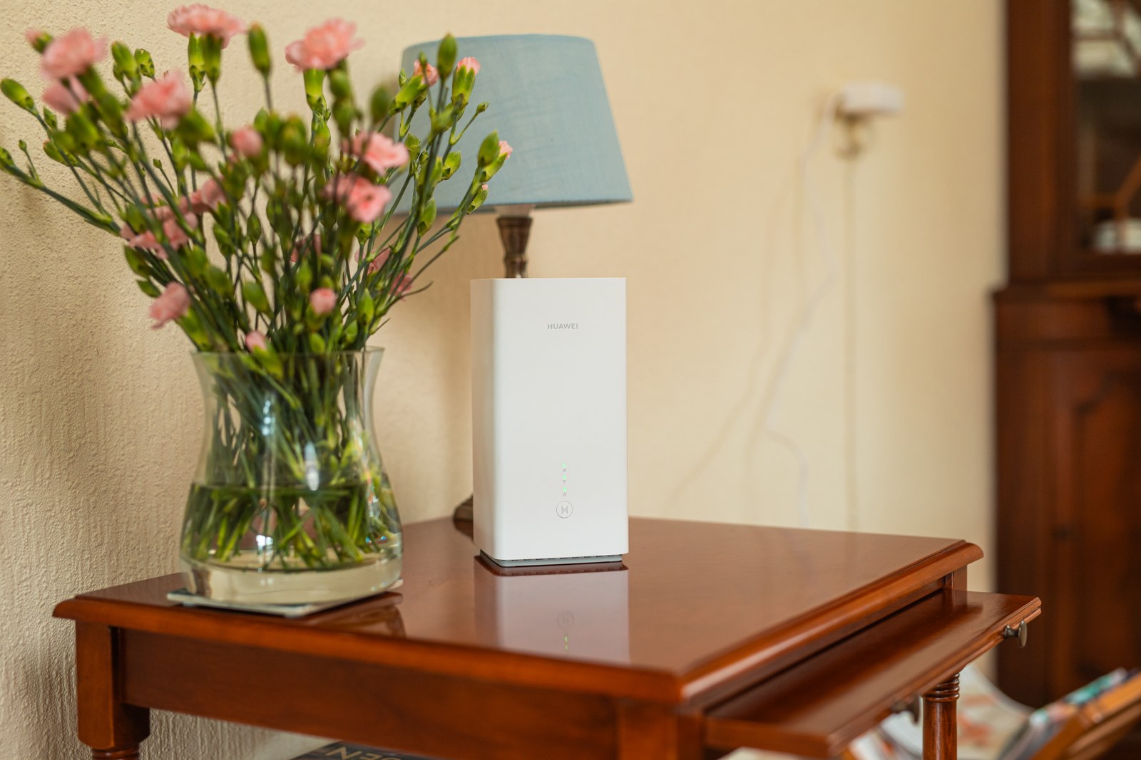 Het 5G-modem op een houten kastje naast een vaas met bloemen in de woonkamer