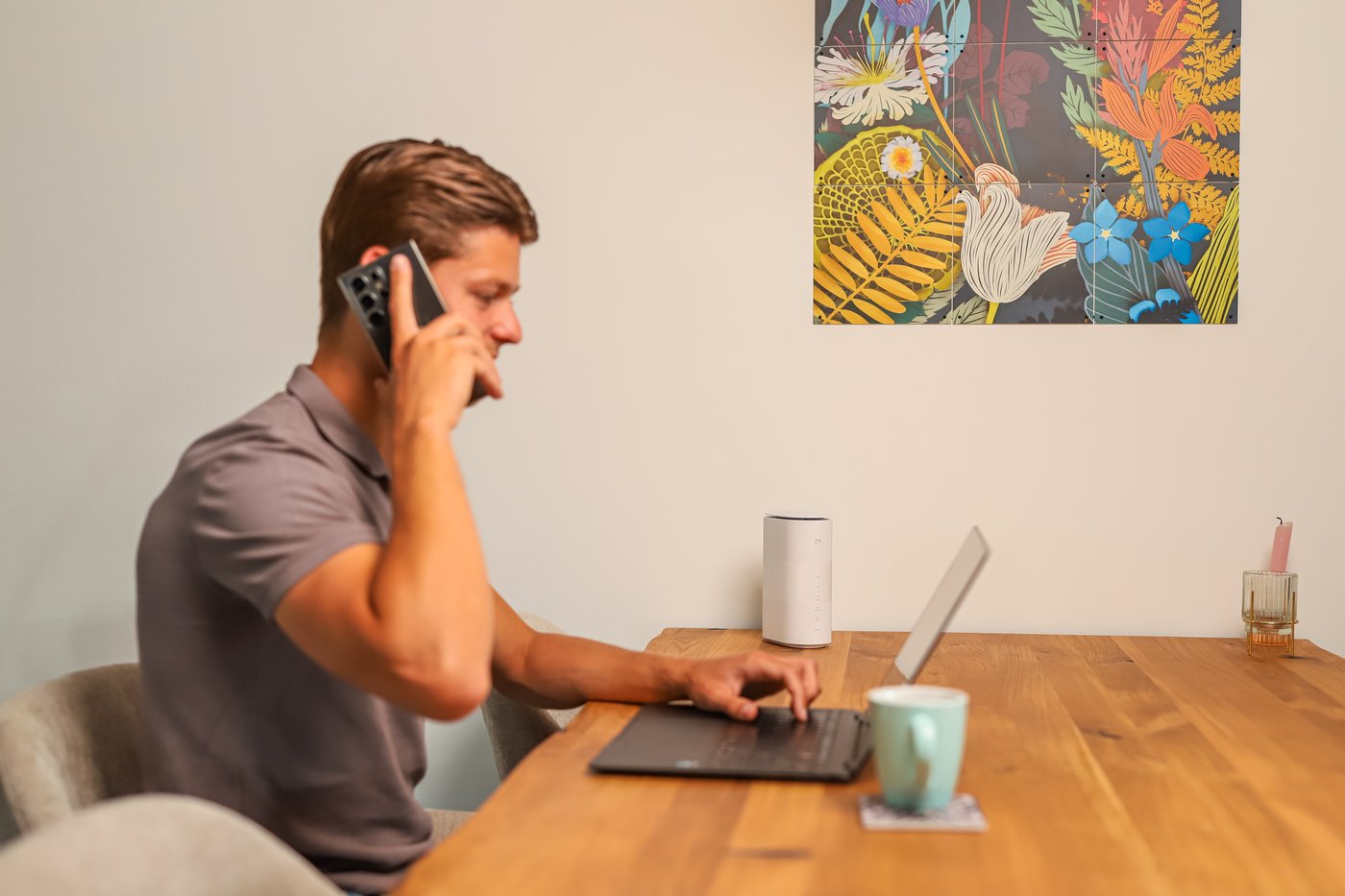 Jonge man belt aan een bureau met een laptop en het modem voor hem