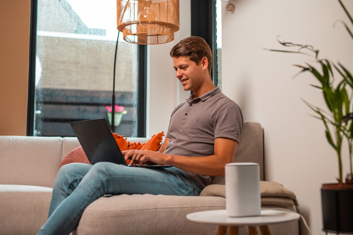 Jonge man op de bank met een laptop, het 5G-modem op het bijzettafeltje