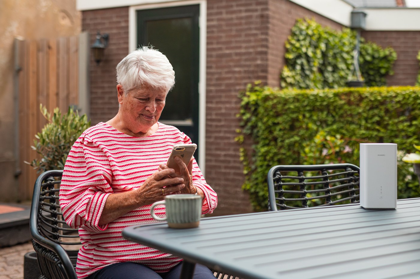 Vrouw belt buiten in de tuin met een mobiele telefoon