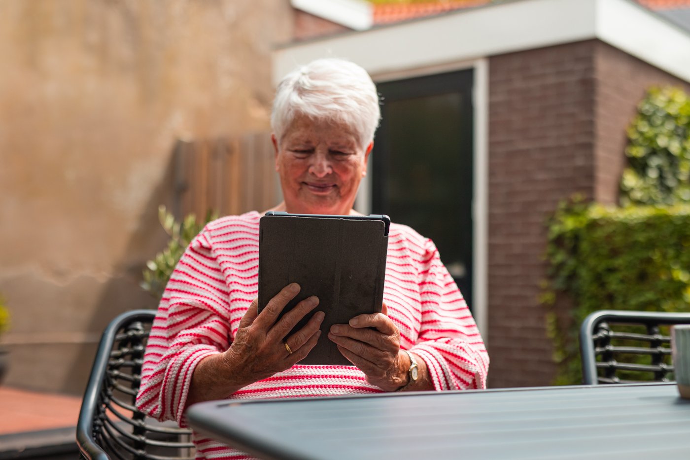 Vrouw zit buiten aan tafel met een tablet