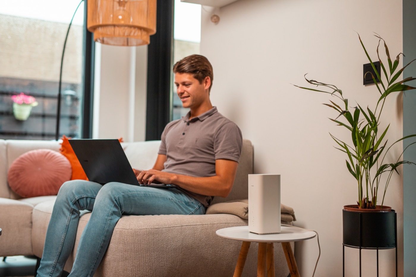 Man werkt op de bank met zijn laptop, het modem staat naast hem