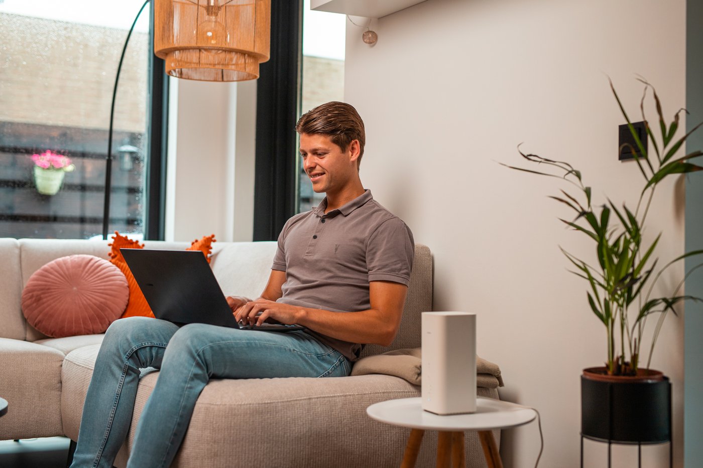 Man werkt op een laptop op de bank, het modem op het tafeltje
