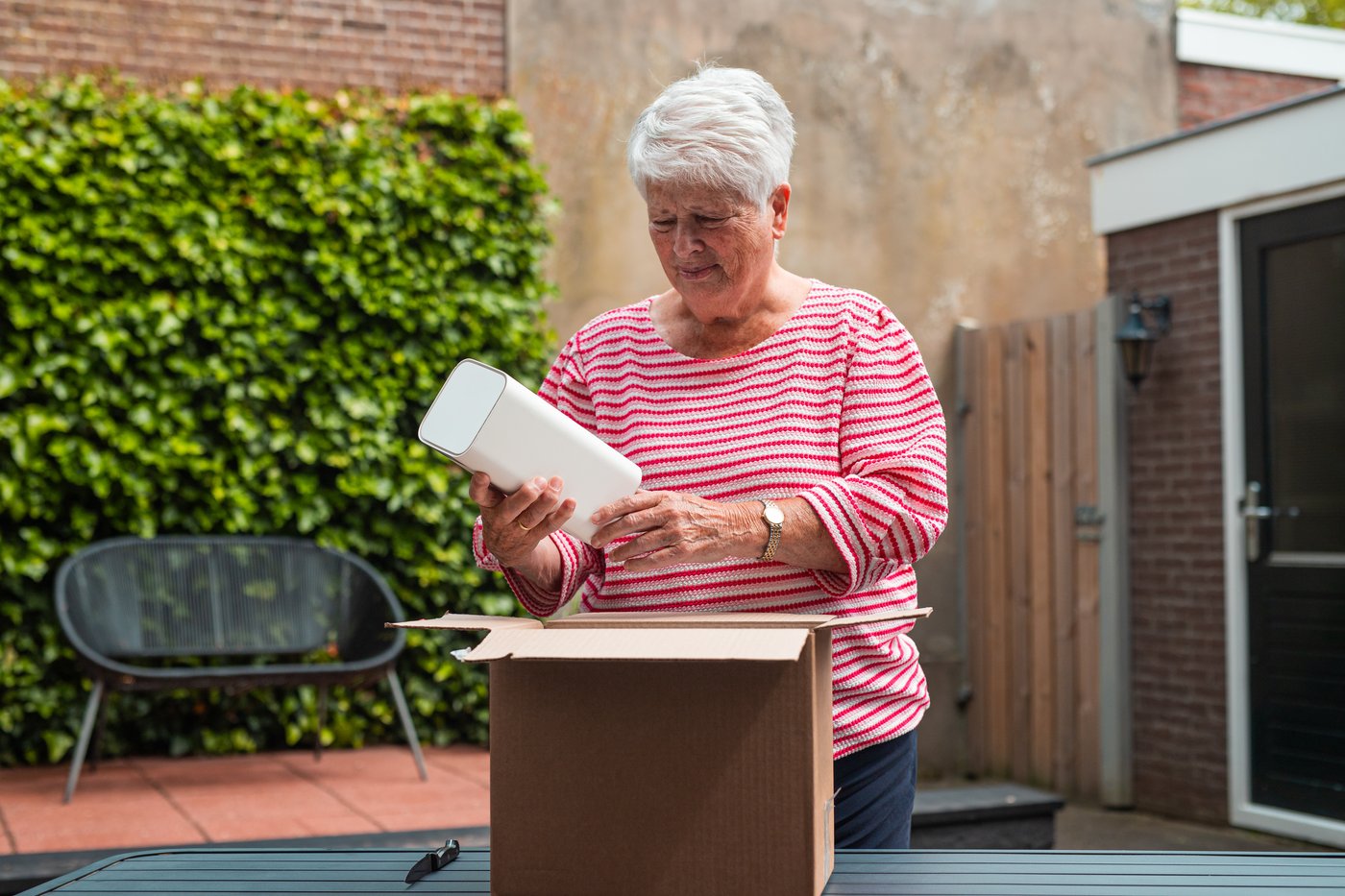 Oudere vrouw pakt het 5G-modem uit de doos in de tuin