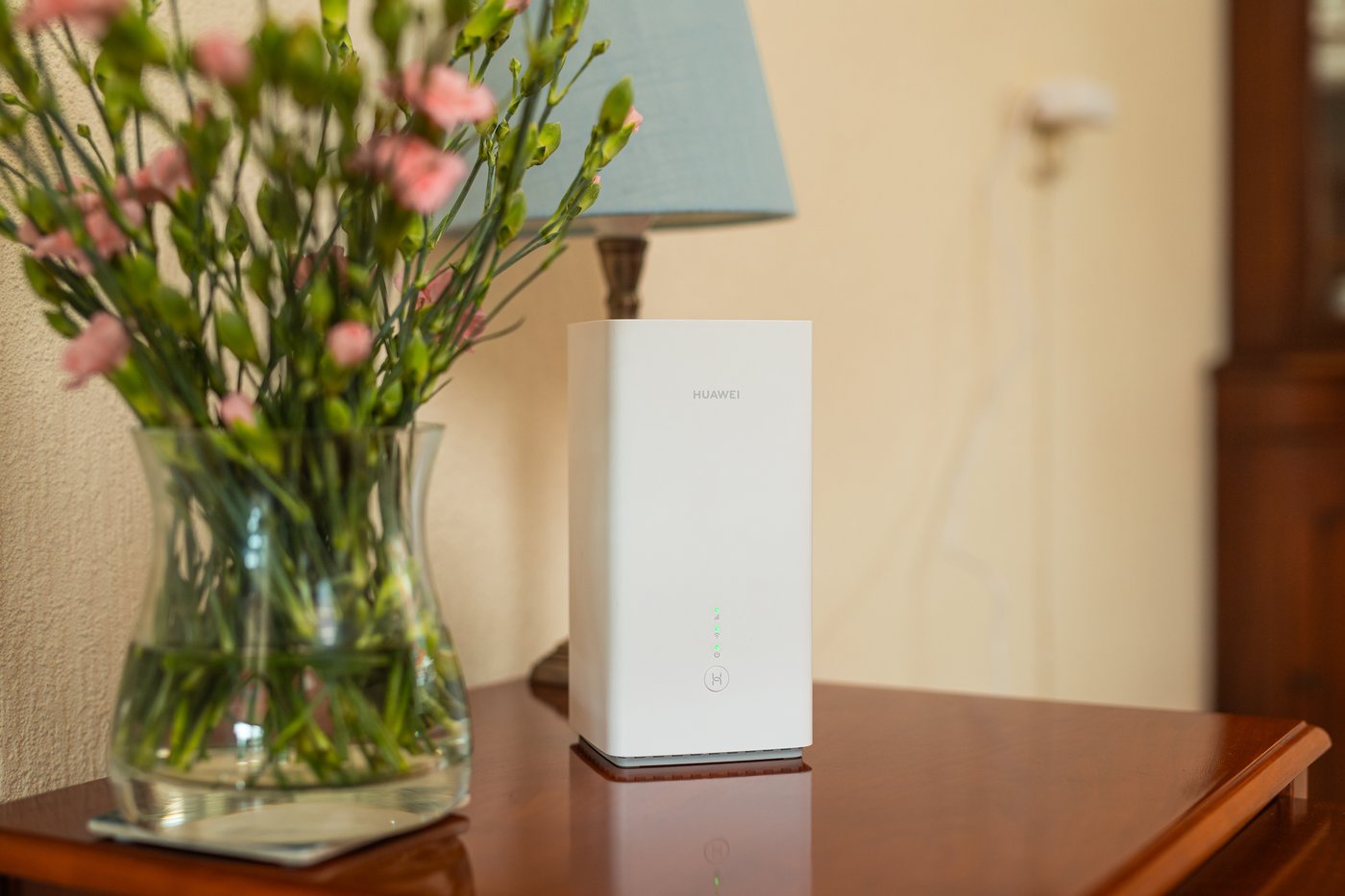 Het 5G-modem op een houten kast naast een vaas met bloemen